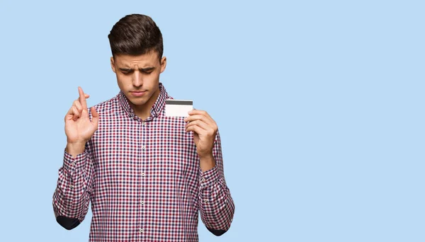 Молодий Чоловік Тримає Кредитну Картку Перетинаючи Пальці Удачу — стокове фото