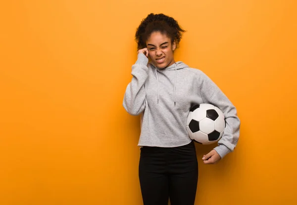 若いフィットネス黒の女性の手で耳をカバー サッカーボールの保持 — ストック写真