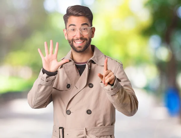 Young Man Wearing Trench Coat Showing Number Six — Stock Photo, Image