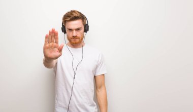 Genç kızıl saçlı adam elini öne koyuyor. Kulaklıkla müzik dinlemek..