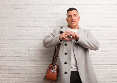 Genç Latin iş adamı elleriyle kalp şekli çiziyor.