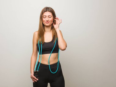 Genç Fitness Rus kadın eller ile kulakları kapsayan. Bir atlama halat tutarak.