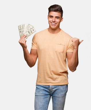 Genç adam yan parmak ile işaret eden dolar tutan