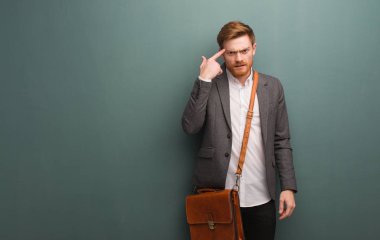 Genç kızıl saçlı iş adamı parmaklarıyla hayal kırıklığı jesti yapıyor.