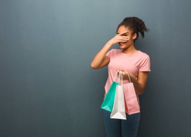 Genç siyahi kadın hem utanmış hem de gülüyordu. Elinde bir alışveriş çantası var..