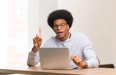 Genç siyahi adam dizüstü bilgisayarını kullanıyor. Harika bir fikri var, yaratıcılık kavramı.