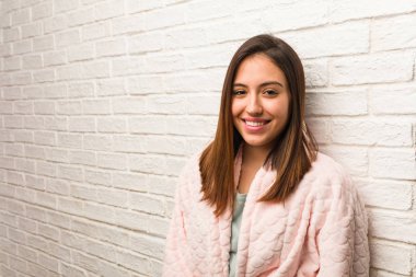 Genç bir kadın pijama giyiyor, neşeli ve gülümsüyor.