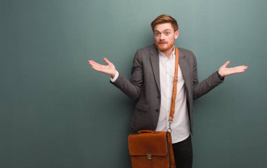 Genç kızıl saçlı iş adamı kuşkulanıyor ve omuz silkiyor.