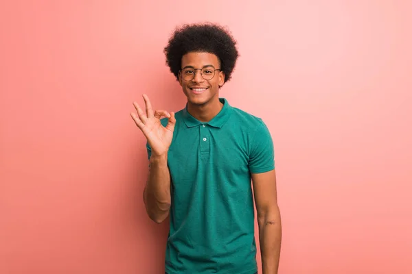 年轻的非洲裔美国人快乐地越过粉红的墙壁 自信地做着一个好的手势 — 图库照片