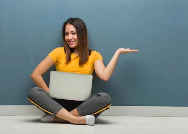 若い女性座っている床にノートパソコンを手で何かを保持 — ストック写真