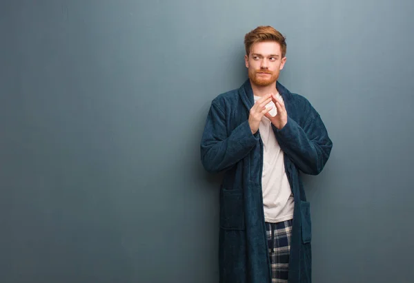 Young redhead man in pajama devising a plan