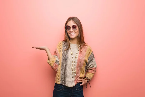 Young hippie woman on pink background holding something with hand