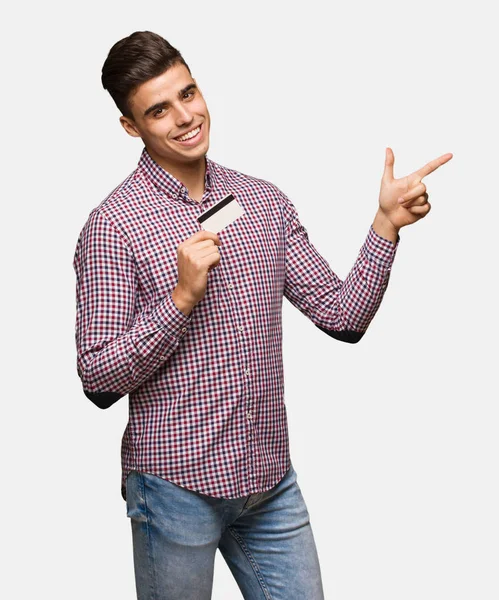Ung Man Håller Kreditkort Som Pekar Sidan Med Finger — Stockfoto