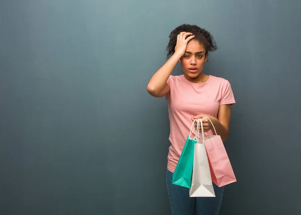 Young black woman tired and very sleepy. She is holding a shopping bags.