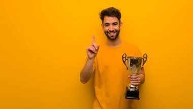 Elinde bir numaralı kupa olan genç adam