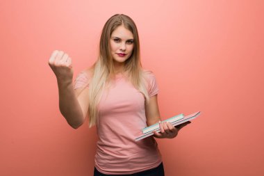 Öne yumruk gösteren genç güzel Rus kız, öfkeli ifade. Kitap tutuyor..