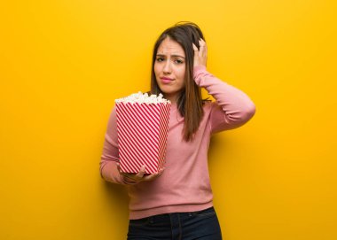 Elinde patlamış mısır kovası tutan genç, tatlı bir kadın endişeli ve bunalmış.