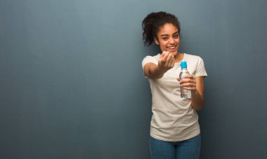 Genç siyahi kadın gelmek için davet ediyor. Elinde bir su şişesi var..