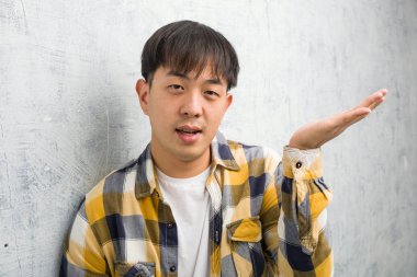 Genç Çinli adam eliyle bir şey tutarak closeup yüz