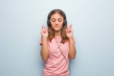 Genç beyaz bir kadın şans dilemek için şans diliyor. Kulaklıkla müzik dinliyor..