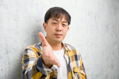 Genç Çinli adam yakından bakıyor. Birini selamlamak için uzanıyor.