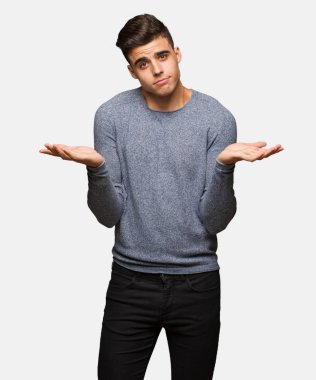 Şüphe ve omuzlarında shrugging genç yakışıklı adam