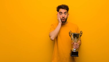 Elinde bir kupa tutan genç adam şaşırdı ve şok oldu.