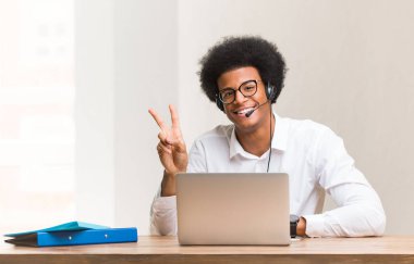 Genç pazarlamacı siyahi adam zafer jesti yapıyor.