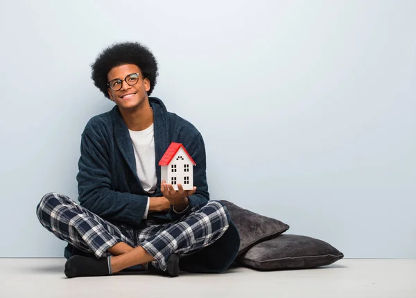 Young Black Man Holding House Model Sitting Floor Smiling Confident — 스톡 사진