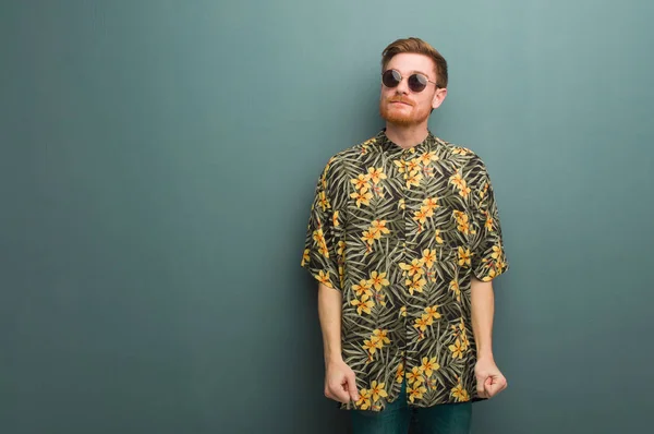 Young redhead man wearing exotic summer clothes dreaming of achieving goals and purposes