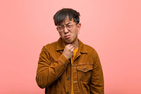 Young chinese man wearing a jacket coughing, sick due a virus or infection