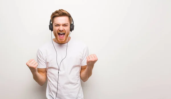 Ung Rödhårig Man Överraskad Och Chockad Lyssna Musik Med Hörlurar — Stockfoto