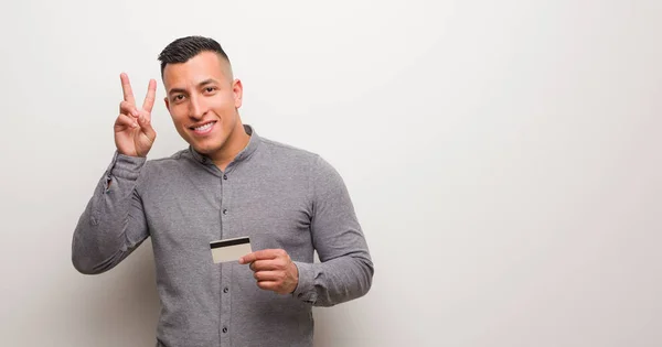 Joven Latino Sosteniendo Una Tarjeta Crédito Divertida Feliz Haciendo Gesto — Foto de Stock