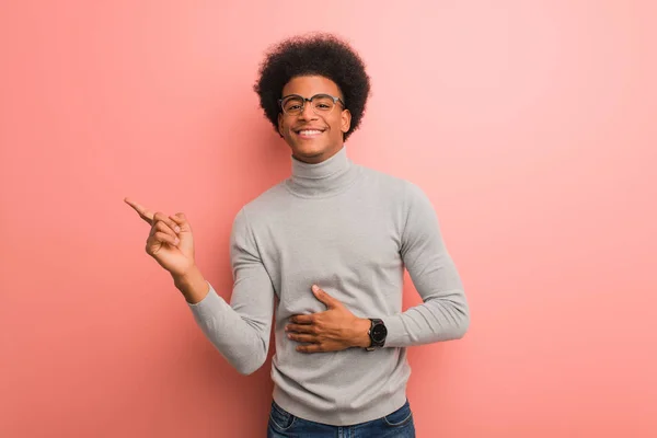 Parmak Ile Yan Gösteren Pembe Bir Duvar Üzerinde Genç Afro — Stok fotoğraf