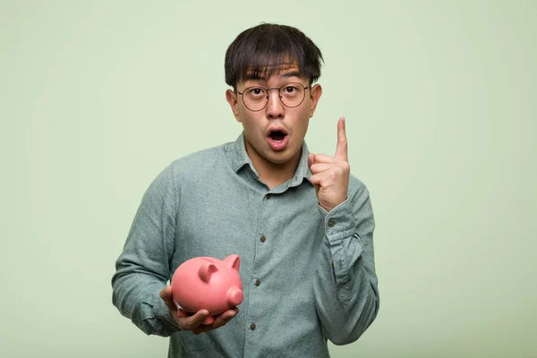 Young Asian Man Holding Piggy Bank Having Great Idea Concept — ストック写真