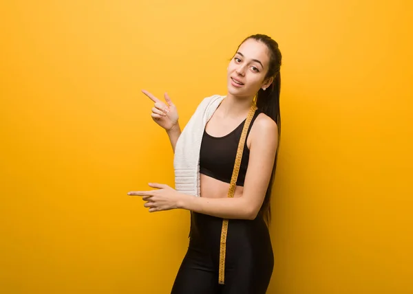 Young fitness girl pointing to the side with finger