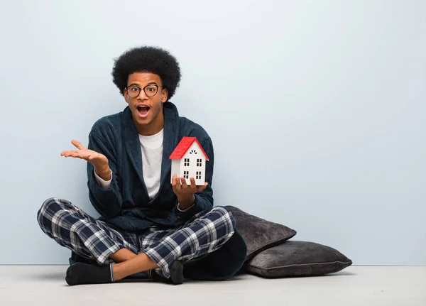 Young Black Man Holding House Model Sitting Floor Celebrating Victory — Stock Photo, Image