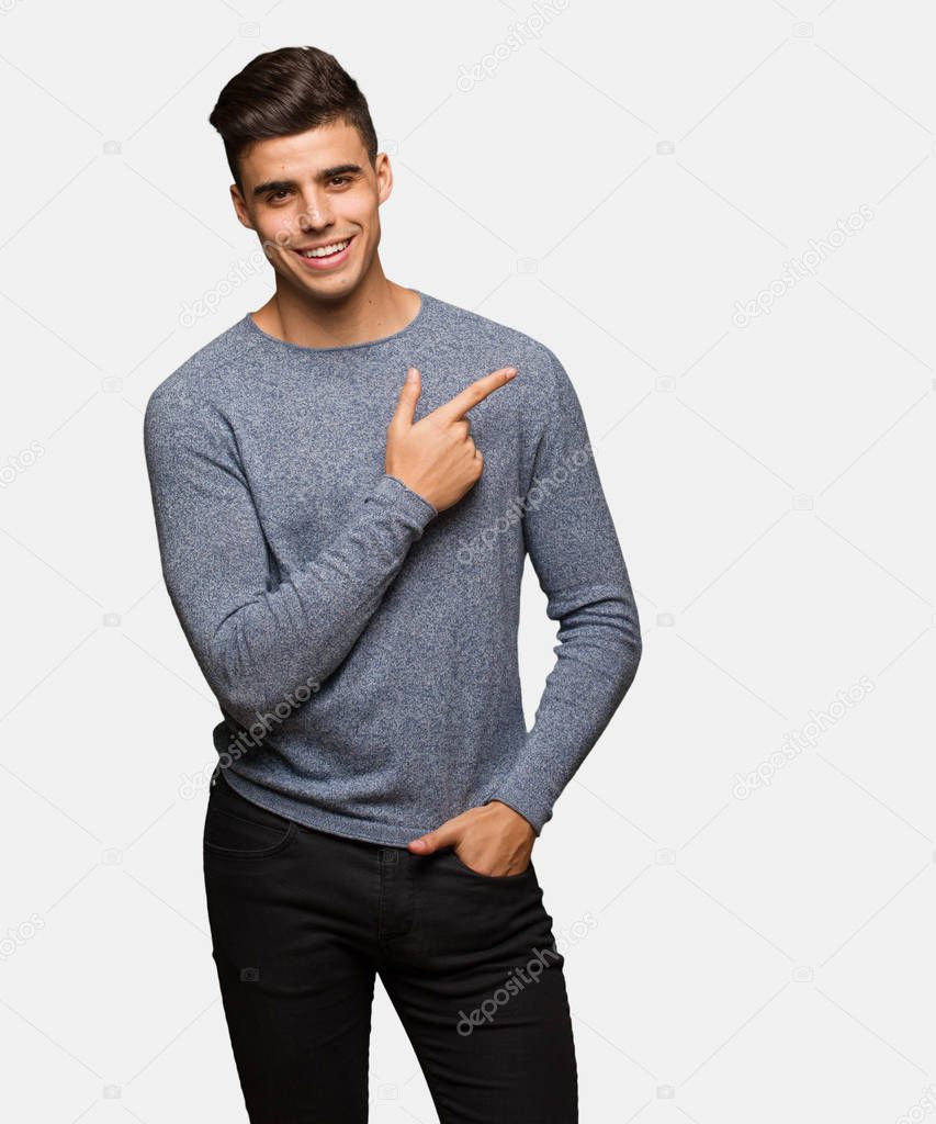 Young handsome man smiling and pointing to the side