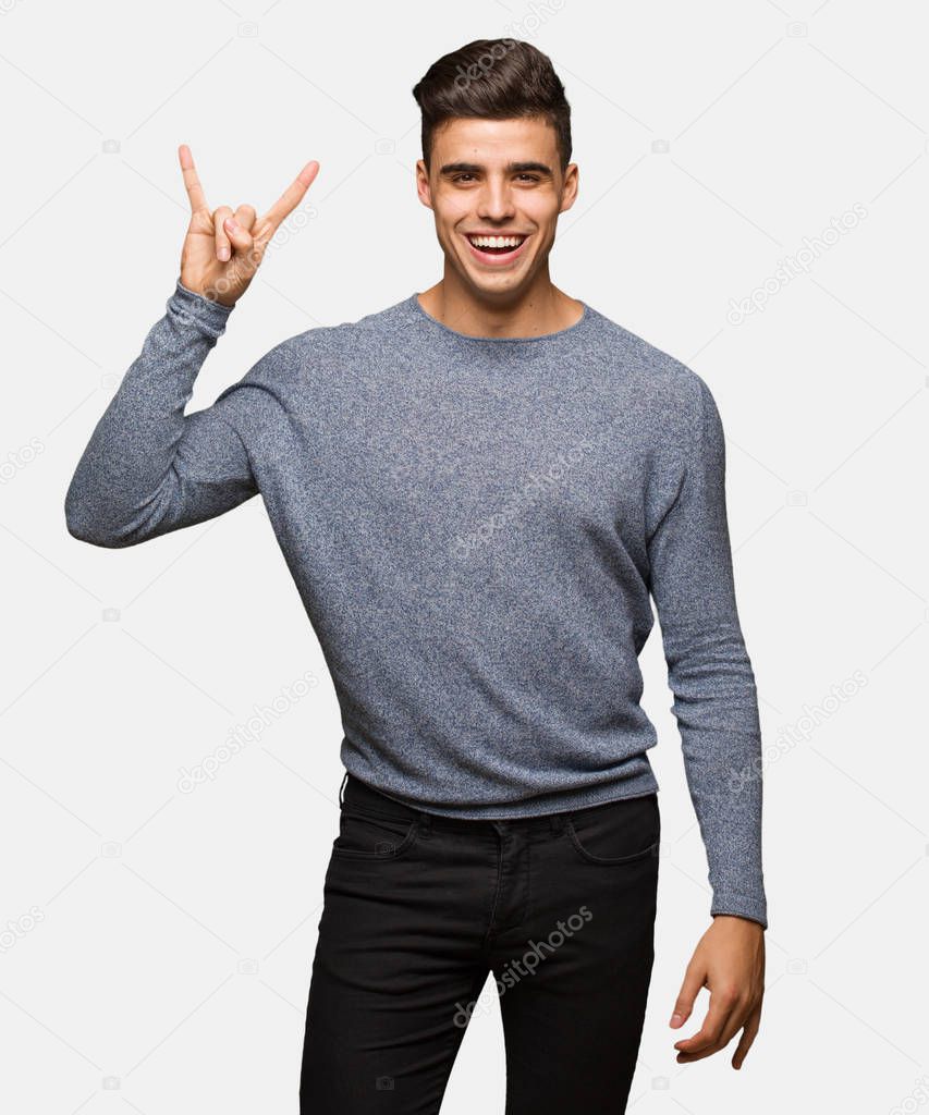 Young handsome man doing a rock gesture