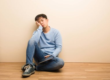 Genç Çinli adam tabletini kullanıyor yorgun ve çok uykulu.