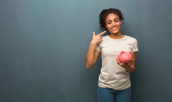 Young Black Woman Smiles Pointing Mouth She Holding Piggy Bank — Stock Photo, Image