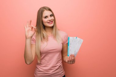 Genç, güzel Rus kız neşeli ve kendinden emin, iyi bir jest yapıyor. Elinde uçak bileti var..