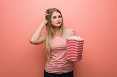 Genç ve güzel Rus kız endişeli ve bunalmış. Elinde patlamış mısır tutuyor..