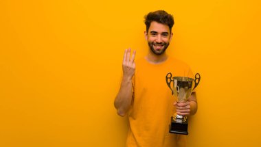 Elinde üç numaralı kupayı tutan genç adam.