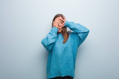 Mavi kazak giyen genç ve güzel bir kadın endişeli ve korkmuş hissediyor.