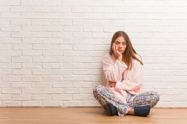 Pijama giyen genç bir kadın yorgun ve çok uykulu.