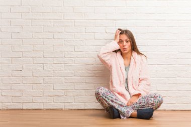 Pijama giyen genç bir kadın yorgun ve çok uykulu.