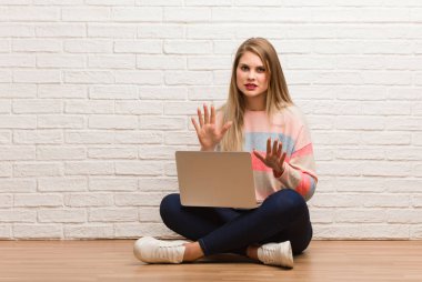 Genç Rus öğrenci bir şey reddederek oturmuş tiksinti jesti yapıyor.