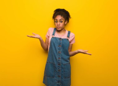 Genç Afro-Amerikan kız şüphe ve omuzlarında shrugging mavi gözleri ile siyah