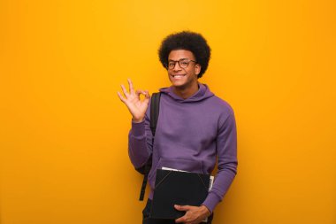 Genç Afro-Amerikan öğrenci neşeli ve kendinden emin iyi bir jest yapıyor.